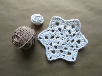 My crocheted snowflake trivet with a small ball of leftover, undyed t-shirt yarn, along with a full ball of t-shirt yarn I dyed using tea bags.
